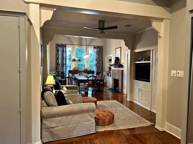 living area with baseboards, visible vents, a ceiling fan, ornamental molding, and dark wood-type flooring