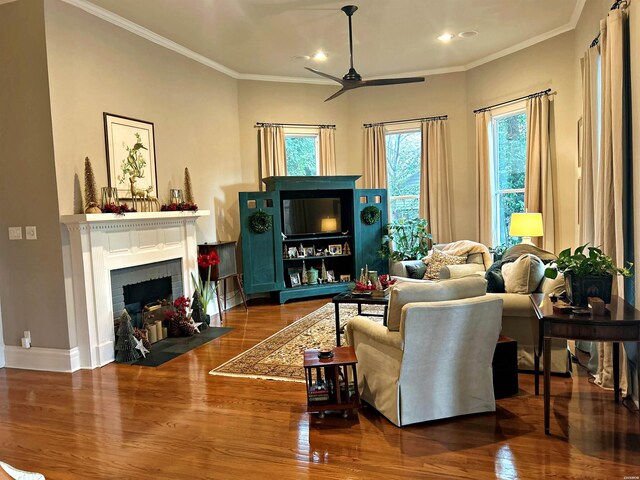 living room with baseboards, a ceiling fan, ornamental molding, wood finished floors, and a brick fireplace