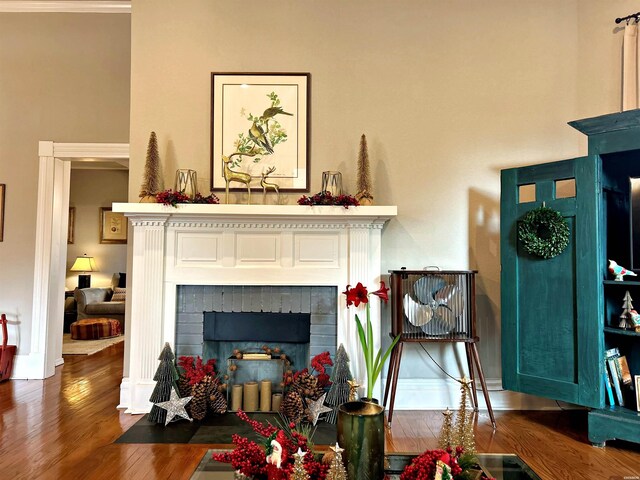 living area with baseboards, wood finished floors, and a tile fireplace