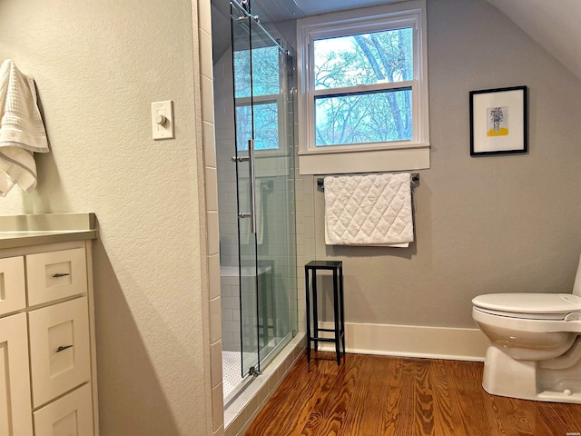 bathroom featuring toilet, wood finished floors, baseboards, vaulted ceiling, and a stall shower