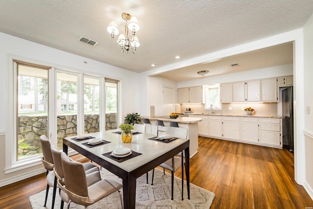 dining space featuring dark wood finished floors, a notable chandelier, visible vents, and a wealth of natural light