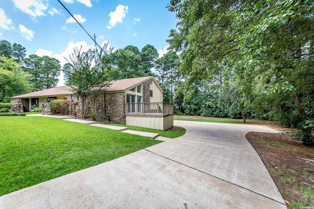 view of front of property featuring stone siding, curved driveway, and a front lawn