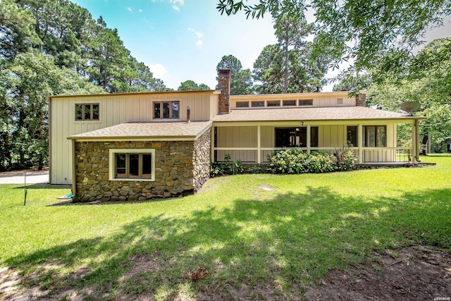 view of front of property featuring stone siding, a front lawn, board and batten siding, and a chimney