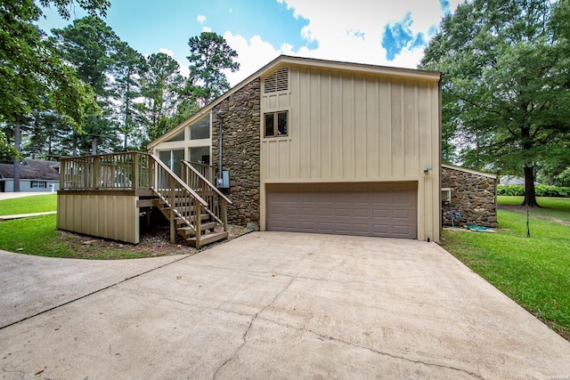 view of front of home featuring board and batten siding, a front yard, a garage, stone siding, and driveway