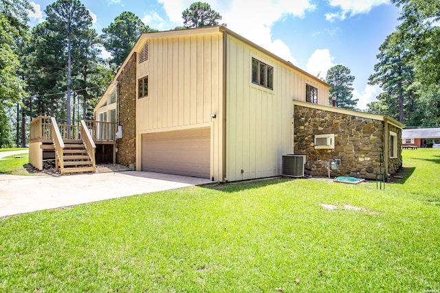 view of property exterior with board and batten siding, cooling unit, driveway, a yard, and an attached garage