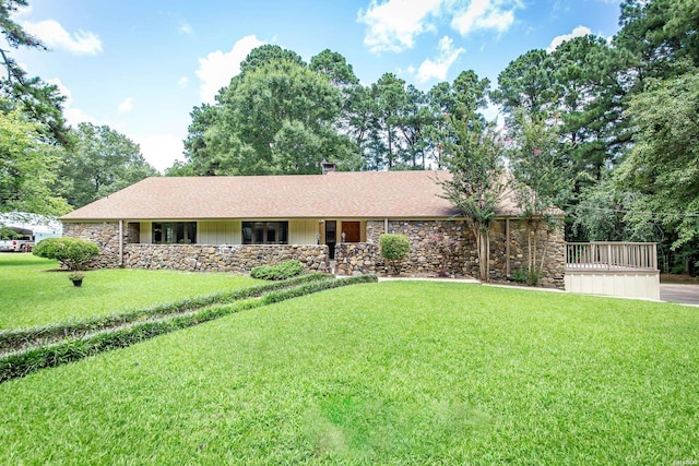 ranch-style house with a shingled roof, a front lawn, stone siding, and a chimney