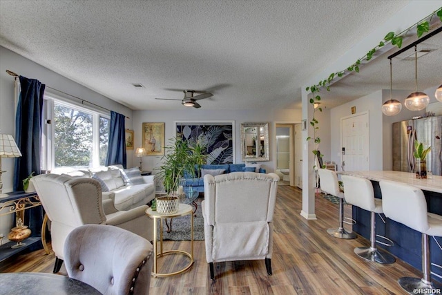 living room featuring a textured ceiling, wood finished floors, and a ceiling fan