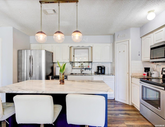 23 Ponferrada Way, Hot Springs Village, AR 71909 - kitchen featuring appliances with stainless steel finishes, a sink, white cabinets, backsplash, and a textured ceiling
