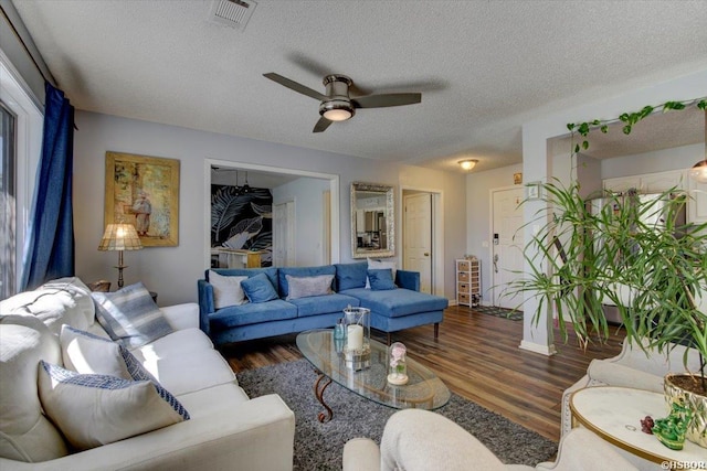 living area with ceiling fan, a textured ceiling, visible vents, and wood finished floors