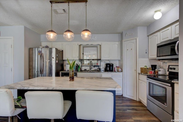 kitchen with white cabinetry, visible vents, tasteful backsplash, and appliances with stainless steel finishes