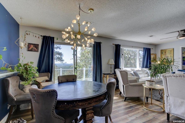 dining area featuring an inviting chandelier, a textured ceiling, visible vents, and wood finished floors