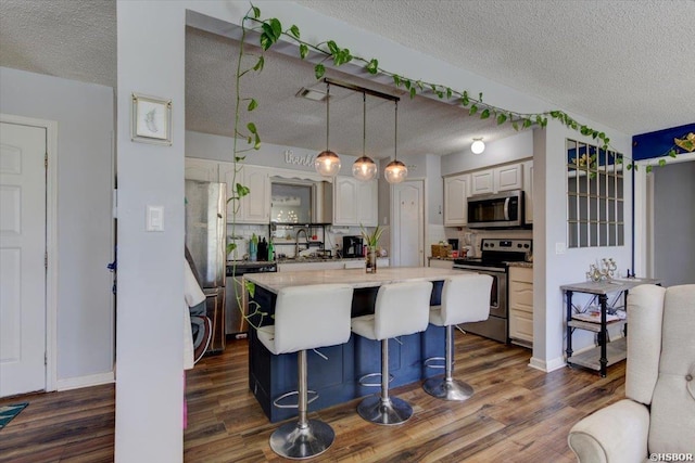 kitchen featuring dark wood-style flooring, stainless steel appliances, a textured ceiling, and light countertops