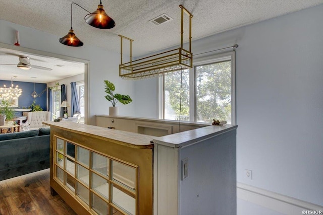 kitchen featuring hanging light fixtures, a textured ceiling, visible vents, and open floor plan