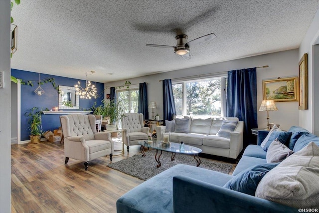 living room featuring a textured ceiling, ceiling fan with notable chandelier, and wood finished floors