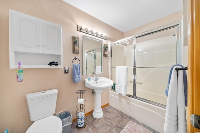 full bath featuring baseboards, bath / shower combo with glass door, toilet, tile patterned floors, and a textured ceiling