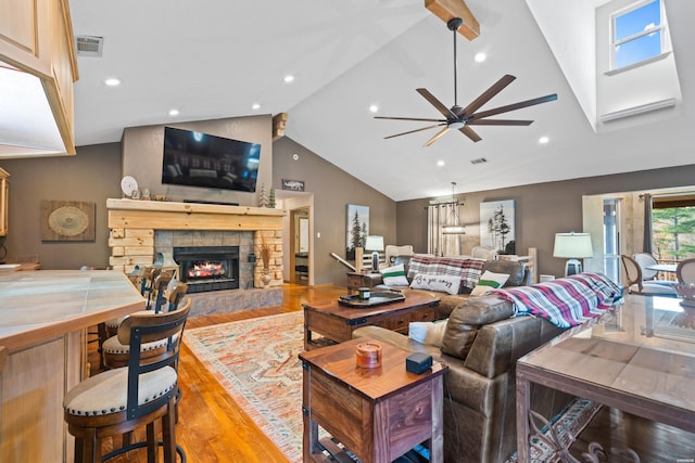 living room with light wood finished floors, a fireplace, visible vents, and high vaulted ceiling