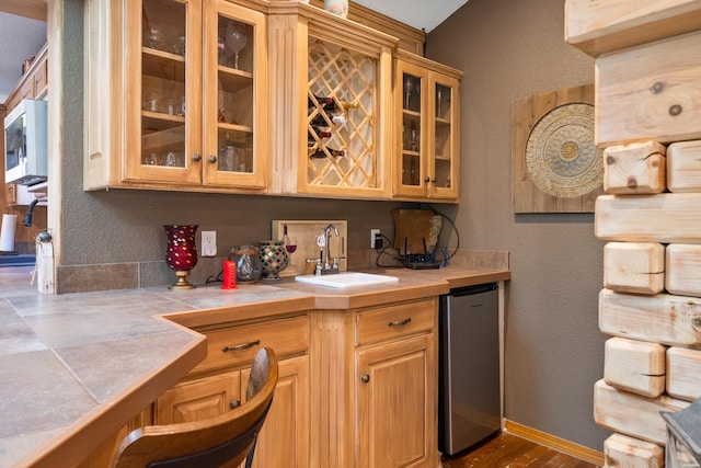 bar with baseboards, a textured wall, refrigerator, a sink, and indoor wet bar