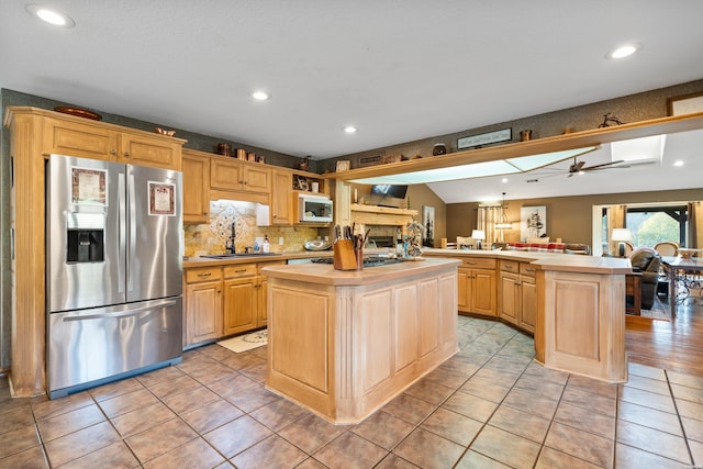 kitchen with a kitchen island, appliances with stainless steel finishes, light countertops, and a sink