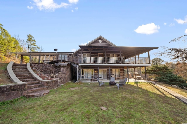 back of house featuring an outdoor fire pit, a wooden deck, a lawn, and a patio