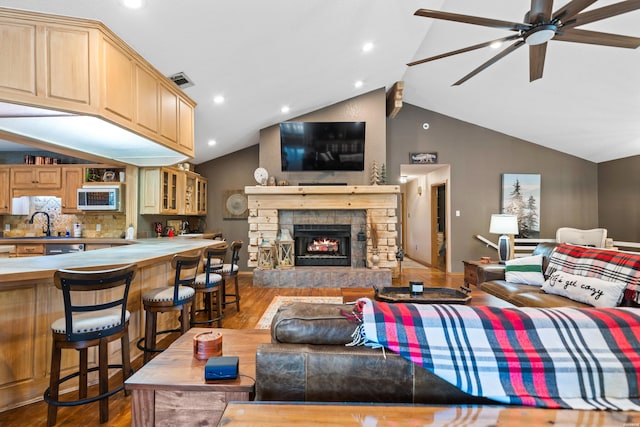 living room with visible vents, lofted ceiling, ceiling fan, wood finished floors, and a fireplace