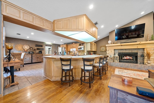 kitchen featuring a breakfast bar, open floor plan, a peninsula, and light brown cabinetry