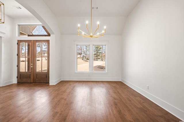 foyer with arched walkways, visible vents, an inviting chandelier, wood finished floors, and baseboards