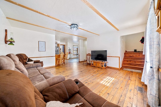 living room with stairway, baseboards, visible vents, and wood finished floors