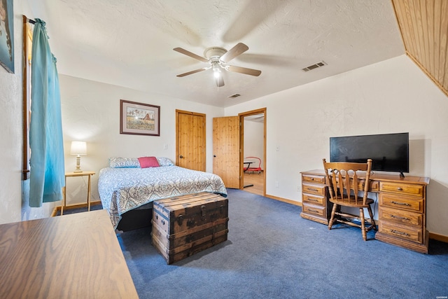 bedroom with a textured ceiling, a ceiling fan, visible vents, baseboards, and dark carpet