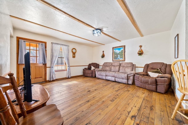 living area featuring light wood-type flooring, beam ceiling, and a textured ceiling