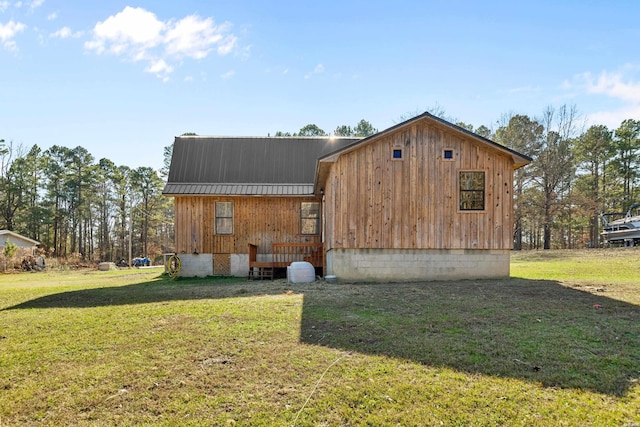 back of house with metal roof and a lawn