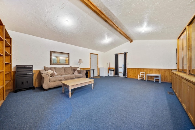 living area featuring vaulted ceiling with beams, wood walls, wainscoting, and a textured ceiling