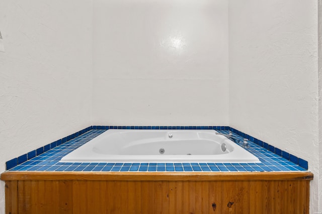 bathroom with a jetted tub and a textured wall