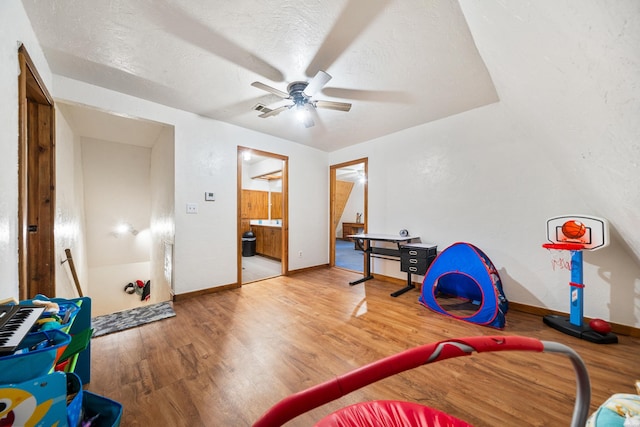 playroom featuring ceiling fan, a textured ceiling, and wood finished floors