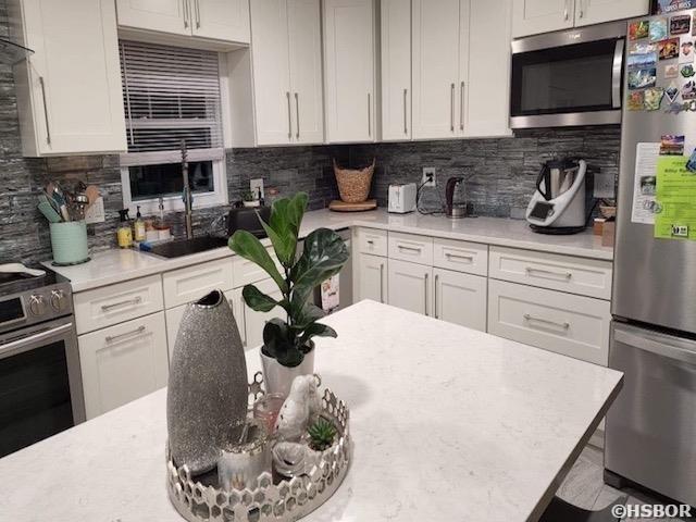 kitchen with stainless steel appliances, light countertops, and white cabinetry