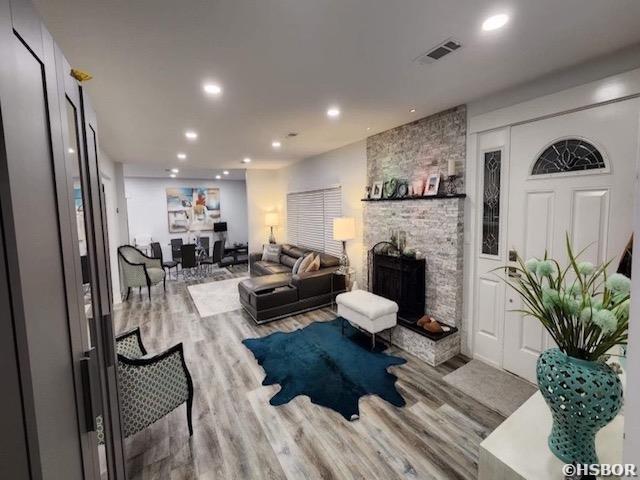 living room with a fireplace, wood finished floors, visible vents, and recessed lighting