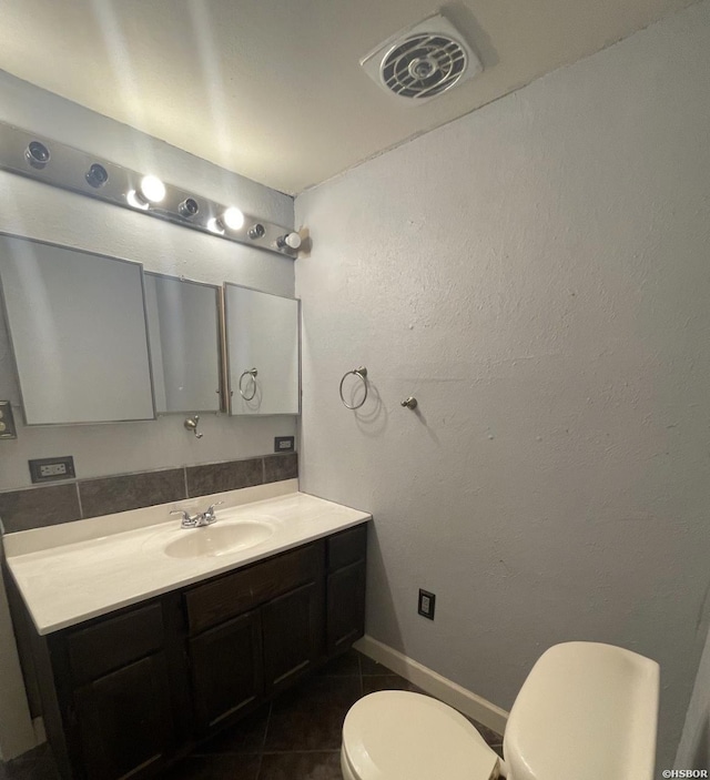 half bath with visible vents, toilet, vanity, tile patterned flooring, and baseboards