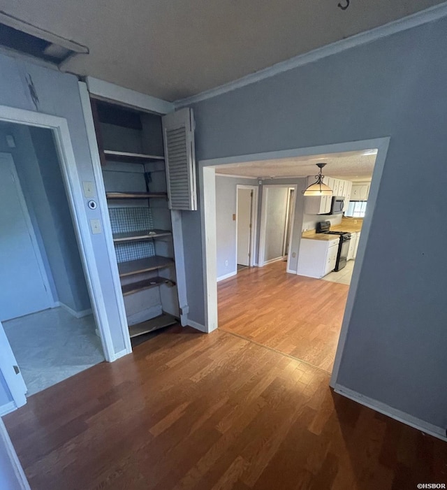 interior space with crown molding, baseboards, and wood finished floors