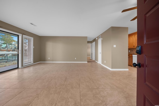 empty room with a ceiling fan, visible vents, baseboards, and light tile patterned floors