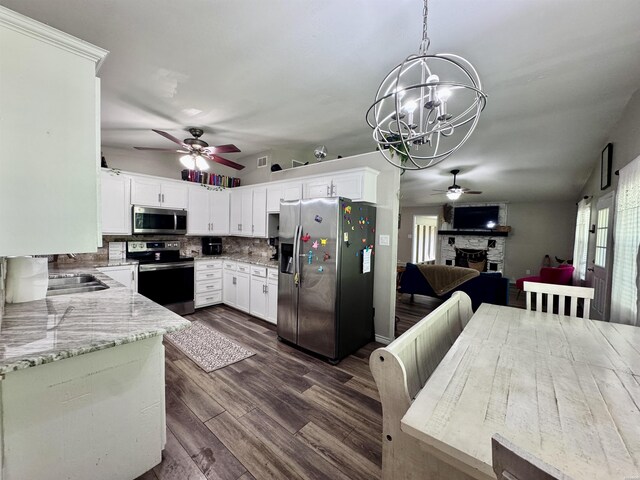 612 Independence, Hot Springs, AR 71913 - kitchen with a stone fireplace, dark wood finished floors, ceiling fan with notable chandelier, backsplash, and stainless steel appliances