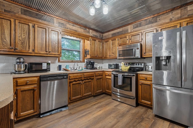 kitchen featuring brown cabinetry, light countertops, a sink, and appliances with stainless steel finishes