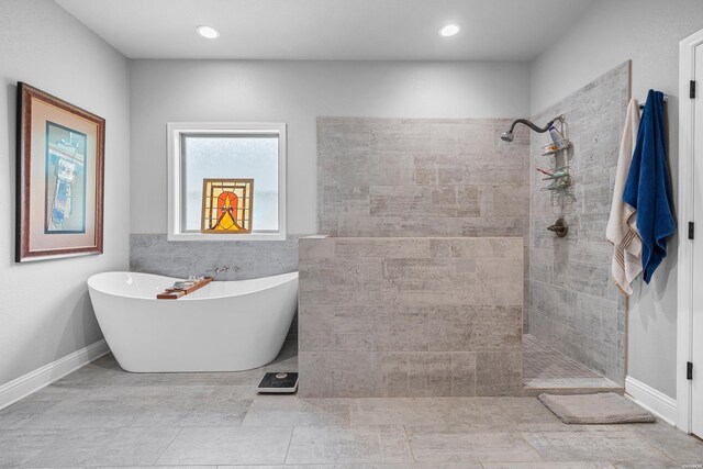 bathroom with baseboards, walk in shower, a freestanding tub, and recessed lighting