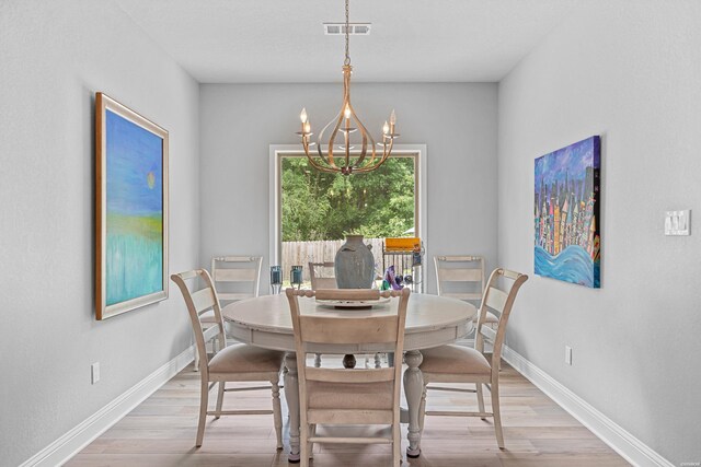 dining room with an inviting chandelier, light wood-type flooring, visible vents, and baseboards