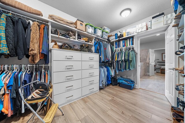 walk in closet with light wood-style floors