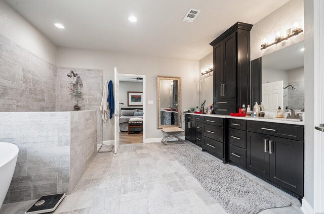 bathroom with baseboards, visible vents, a freestanding bath, vanity, and recessed lighting