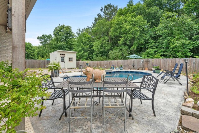 view of patio with an outbuilding, a fenced backyard, a fenced in pool, a storage unit, and outdoor dining space