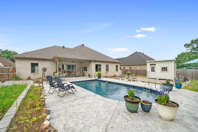 view of pool with a patio, a fenced backyard, an outdoor structure, a ceiling fan, and a fenced in pool