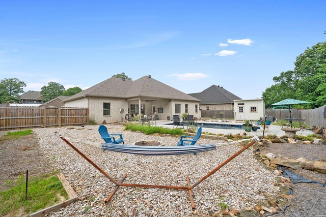 rear view of property with a patio, a swimming pool, an outdoor structure, and a fenced backyard