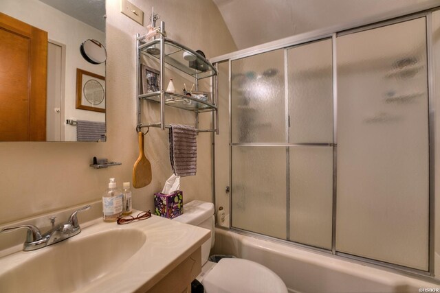 bathroom with enclosed tub / shower combo, vanity, and toilet