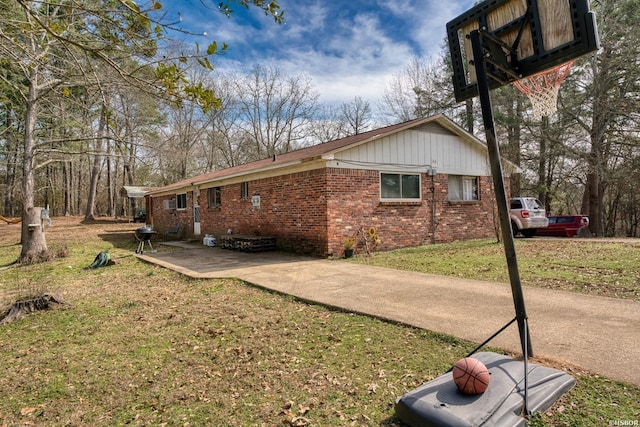 view of property exterior featuring brick siding, a lawn, and a patio