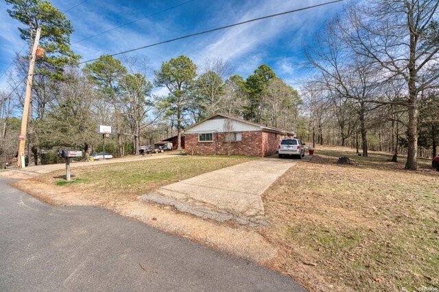 ranch-style house with concrete driveway, brick siding, and a front lawn